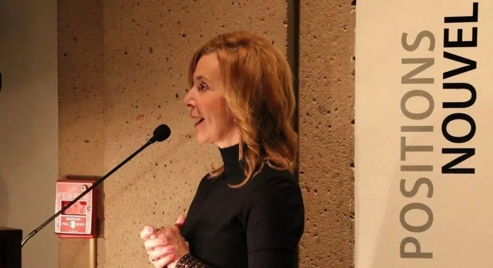 A woman in black shirt standing at podium.