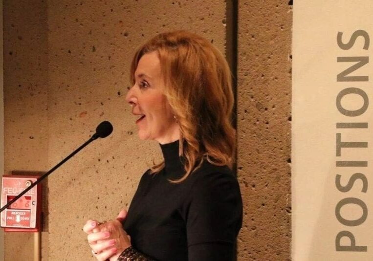 A woman in black shirt standing at podium.